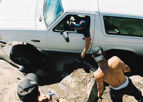 1995 Ford Bronco - A white 1995 Ford Bronco is being helped out of a muddy ditch by onlookers.