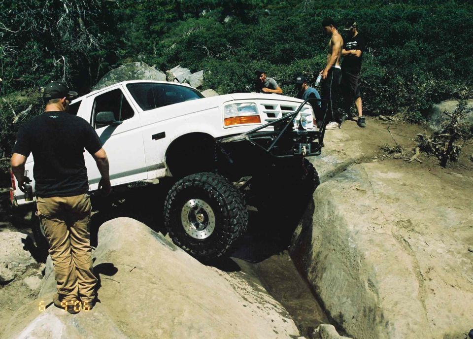 1995 Ford Bronco navigating a rocky off-road trail with people watching