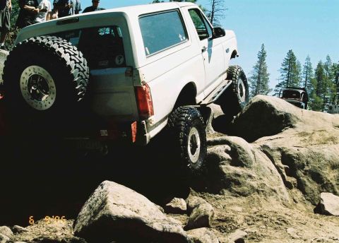 1995 Ford Bronco - This modified SUV is navigating a challenging rocky terrain, with another vehicle in the distance.