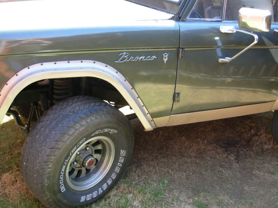 Front fender of a green early Ford Bronco with Bronco emblem