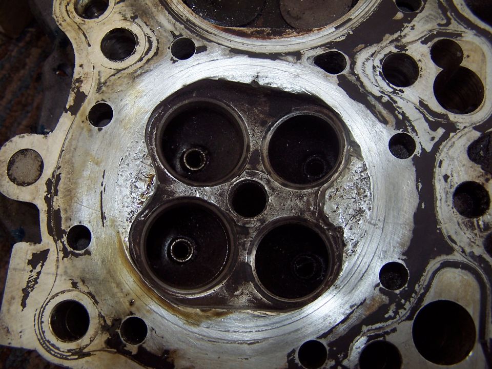 Close-up of an engine cylinder head with four visible combustion chambers
