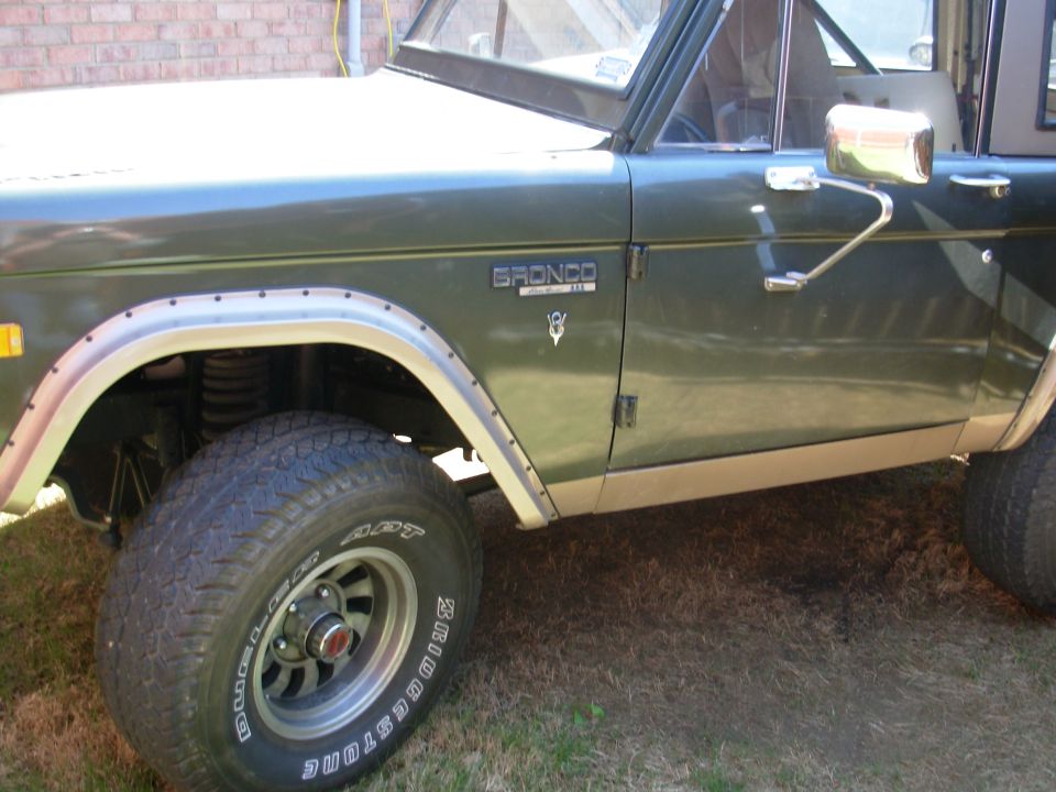 Green Ford Bronco door fender and front wheel under shelter