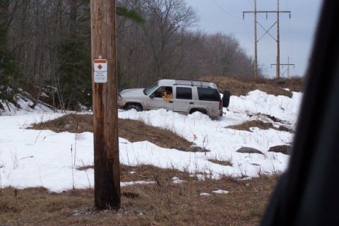 2000 Chevrolet Tahoe - A white SUV is stuck in a snow-covered ditch near a utility pole.