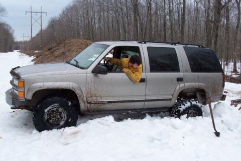 2000 Chevrolet Tahoe - A silver SUV is stuck in deep snow, with a person leaning out the driver's side window.