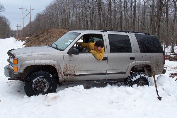Silver SUV stuck in snow, driver leaning out window