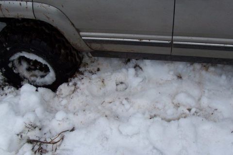 2000 Chevrolet Tahoe - Vehicle tire stuck in snow and mud, showing side panel and trim.