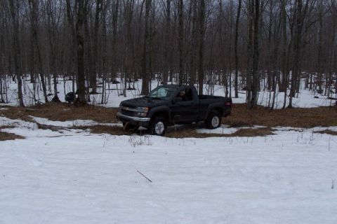 2000 Chevrolet Tahoe - A black pickup truck is parked in a snowy forest clearing, surrounded by bare trees.