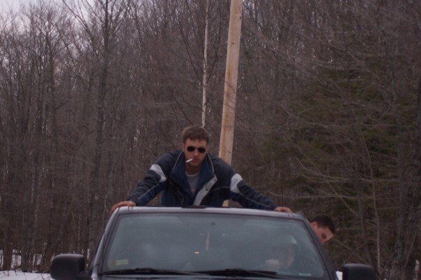 Man standing on car roof, smoking cigarette