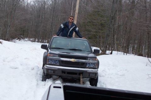 2000 Chevrolet Tahoe - Man on roof of Chevrolet Colorado pickup truck stuck in snowy terrain, with another vehicle nearby.