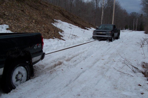 Black pickup truck being towed in snow, front view. 2003 model