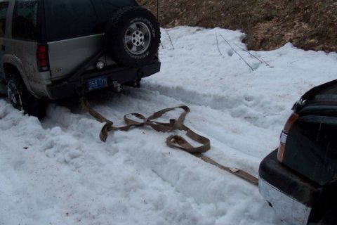 2000 Chevrolet Tahoe - Two SUVs are stuck in the snow, connected by a tow strap.