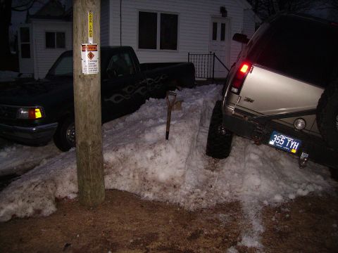 2000 Chevrolet Tahoe - Two trucks are stuck in a snowbank, one with flame decals and the other a silver SUV.