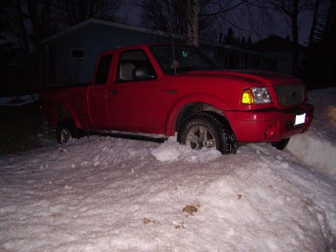 2000 Chevrolet Tahoe - Red Ford Ranger pickup truck stuck in snow, likely during winter conditions.
