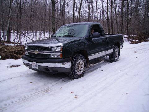 2000 Chevrolet Tahoe - A pickup truck navigates a snow-covered path in a wooded area.