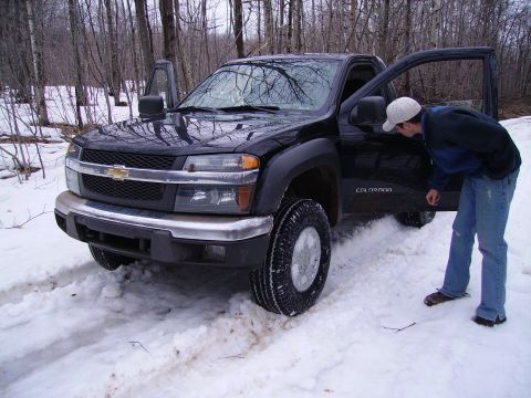2000 Chevrolet Tahoe - A person inspects a black Chevrolet Colorado pickup truck stuck in the snow.