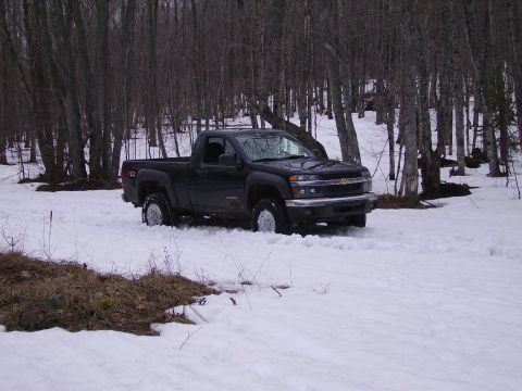 2000 Chevrolet Tahoe - A black pickup truck is partially submerged in snow amidst a wooded area.