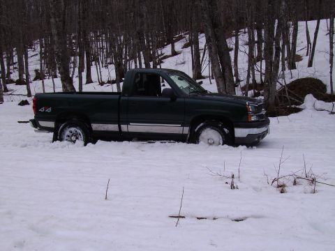 2000 Chevrolet Tahoe - A dark green pickup truck is stuck in deep snow, with only its front half visible.
