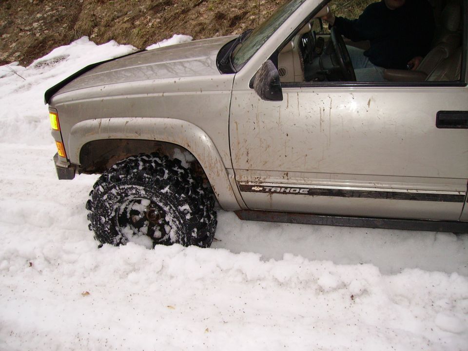 Silver SUV stuck in snow, "TAHOE" badge visible
