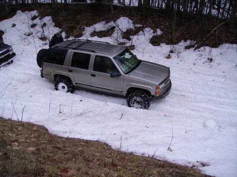 2000 Chevrolet Tahoe - A silver SUV is stuck in the snow, with another vehicle partially visible in the background.