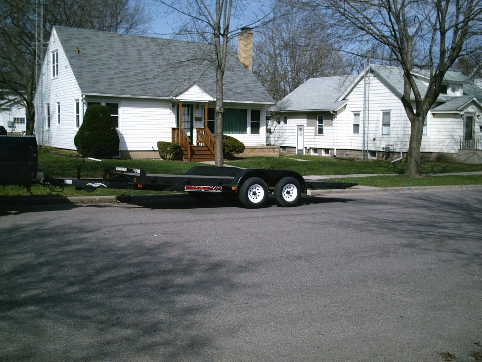 black tandem axle trailer parked on street in front of houses