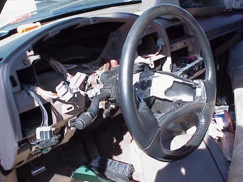 1993 Ford Bronco - The interior of a car shows a disassembled dashboard with many exposed wires and the steering wheel.