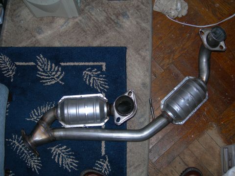 1992 Ford Taurus - A catalytic converter assembly is shown laid out on a rug and wooden floor.