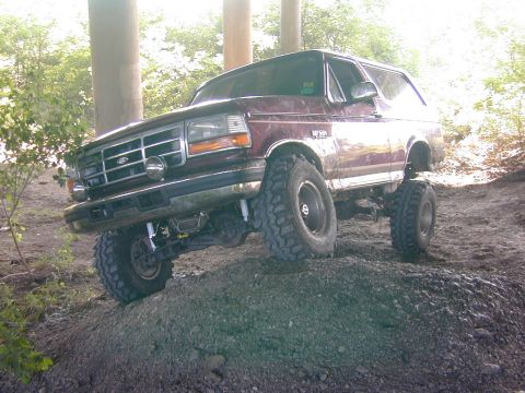 1996 Ford Bronco - This maroon SUV, likely from the early to mid-1990s, navigates a challenging off-road course.
