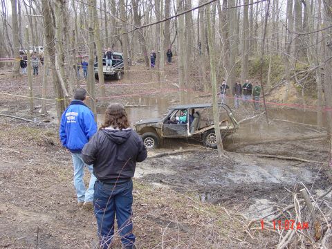 1995 Dodge 1500 - An off-road buggy navigates a challenging mud pit during an event, with spectators observing the action.