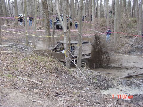 1995 Dodge 1500 - An off-road truck navigates a muddy obstacle course with spectators watching in the background.