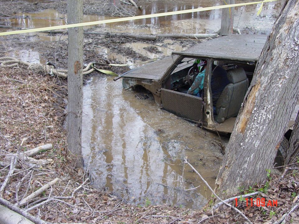 Truck stuck in mud, driver visible in interior