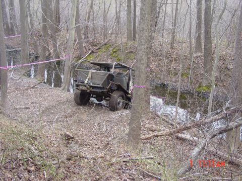 1995 Dodge 1500 - Modified off-road vehicle navigating a wooded trail next to a flowing stream.