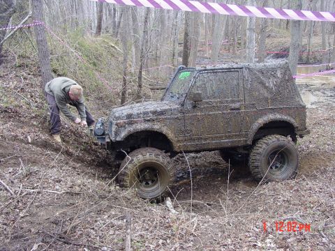 1995 Dodge 1500 - Off-road vehicle covered in mud during an event, with a person working on the front winch.