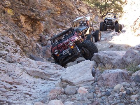 1986 Ford Bronco - Multiple off-road vehicles traverse a challenging rocky terrain in a canyon.