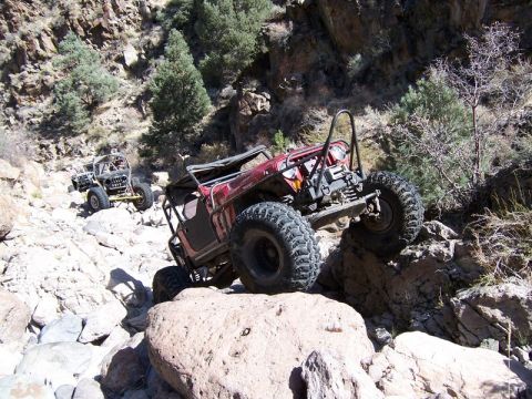 1986 Ford Bronco - Off-road vehicles tackle a challenging rocky terrain in a canyon.