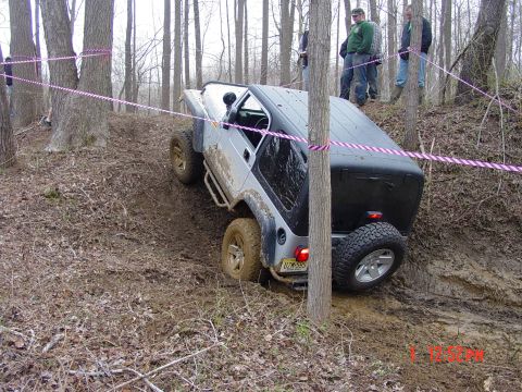 1995 Dodge 1500 - A Jeep Wrangler navigates a challenging, muddy off-road course marked with pink tape.