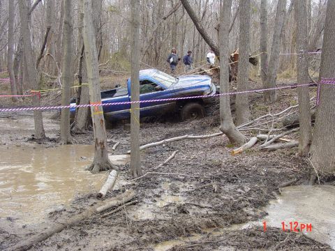 1995 Dodge 1500 - A blue 1995 Dodge 1500 is stuck in the mud and trees, likely during an off-road competition.