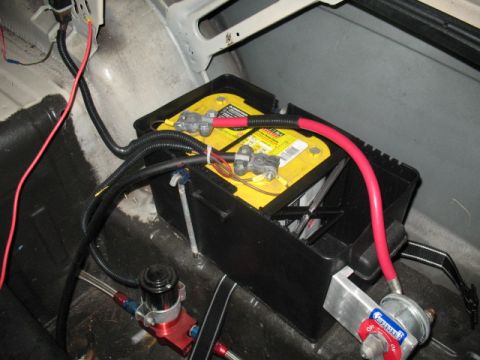 1985 Ford LTD Crown Victoria - Close-up view of a car battery and its associated wiring, along with some fuel system components.