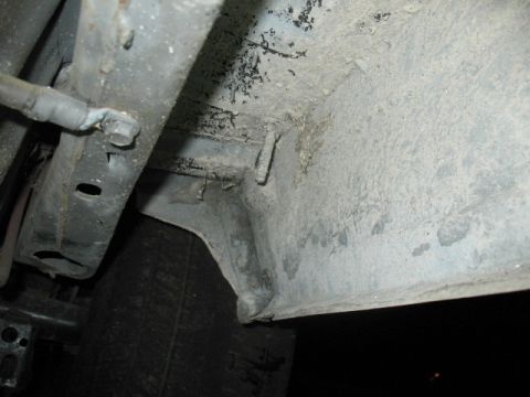 1985 Ford LTD Crown Victoria - Close-up view of a vehicle's dirty undercarriage, revealing structural components and suspension parts.