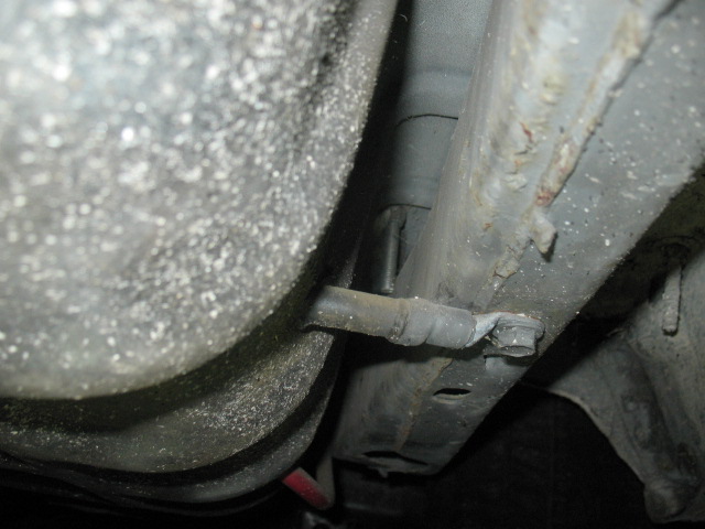 Underside view of vehicle fuel tank and frame with visible rust