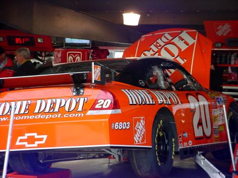 1993 Ford Mustang - A race car with Home Depot sponsorship is parked in a garage, possibly undergoing maintenance.