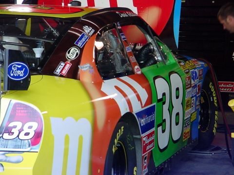 1993 Ford Mustang - Race car with M&M's livery and sponsor decals, number 38, in a garage setting.