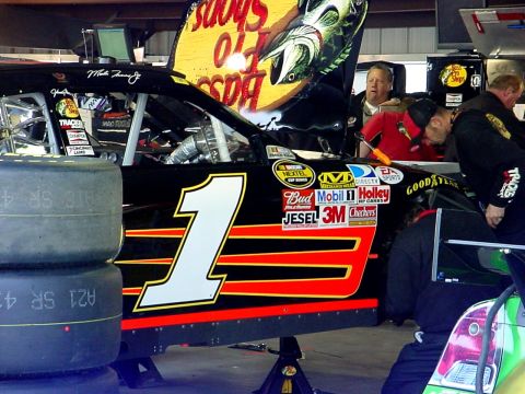 1993 Ford Mustang - A race car with the number 1 and sponsor decals is being worked on in a garage.