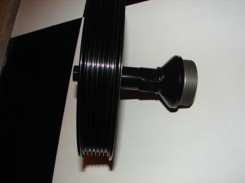 1992 Ford Taurus - This black pulley with ribbed grooves and a threaded shaft is a vehicle part.