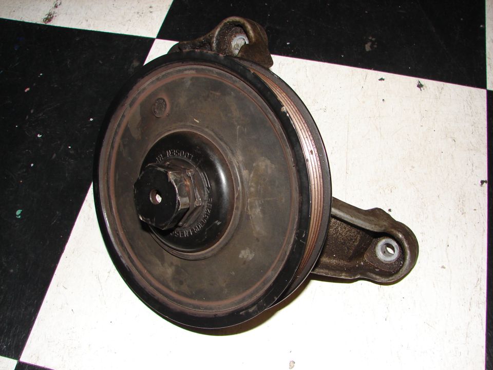 Power steering pump pulley with hex bolt in center. Some text is visible on the pulley