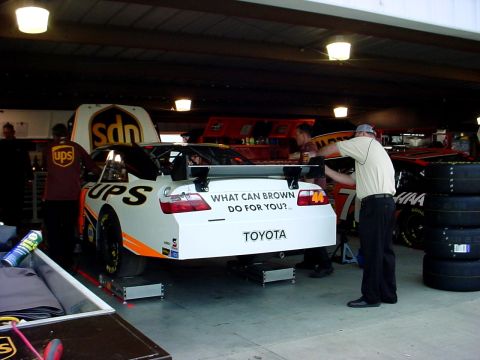 1993 Ford Mustang - A race car with UPS branding and a Toyota logo is being worked on in a garage pit area.