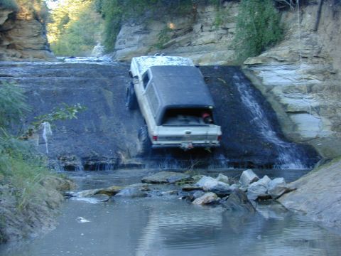 1996 Ford Bronco - Pickup truck navigating a challenging off-road waterfall descent.
