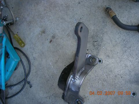 1996 Ford Bronco - Metal bracket with rubber bushing and mounting holes sits on a concrete surface.