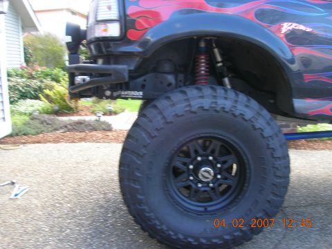 1996 Ford Bronco - This heavily modified truck features custom flame decals and oversized tires, obscuring its original year and model.