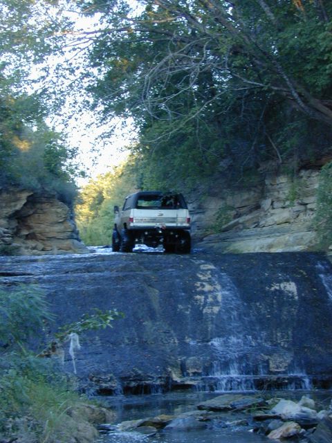 1996 Ford Bronco - A vehicle navigates a challenging rocky path with a small waterfall.