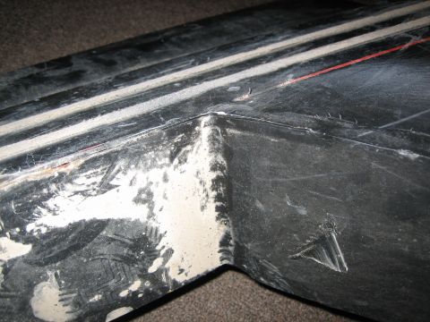 1995 Ford Bronco - This is a close-up view of a damaged black plastic trim piece, showing wear and tear.